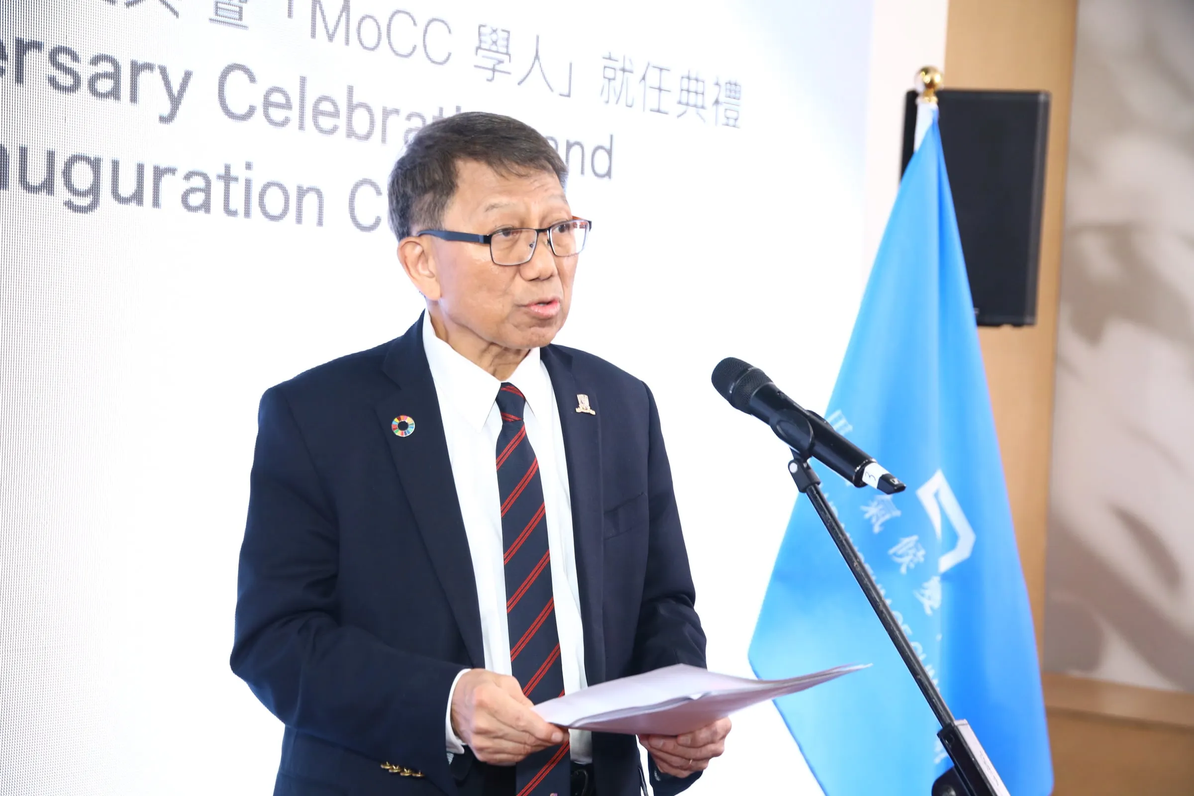A speaker in a suit and tie addressing the ceremony from a lectern